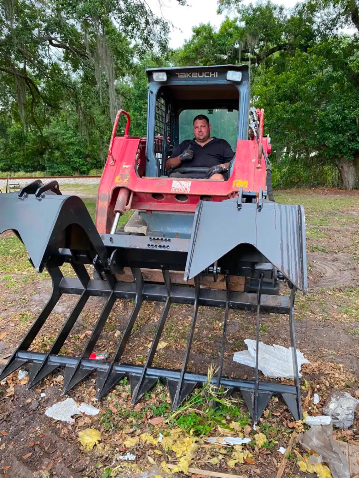 Nick, owner of Bargain Junk Removal, operating a Takeuchi track loader with a heavy-duty grapple attachment on a Polk County demolition job.